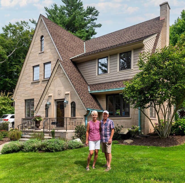 A couple standing in front of their home with a repaired roof